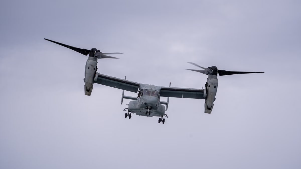 V-22 Osprey tiltrotor aircraft flying through cloudy sky, wings horizontally configured.